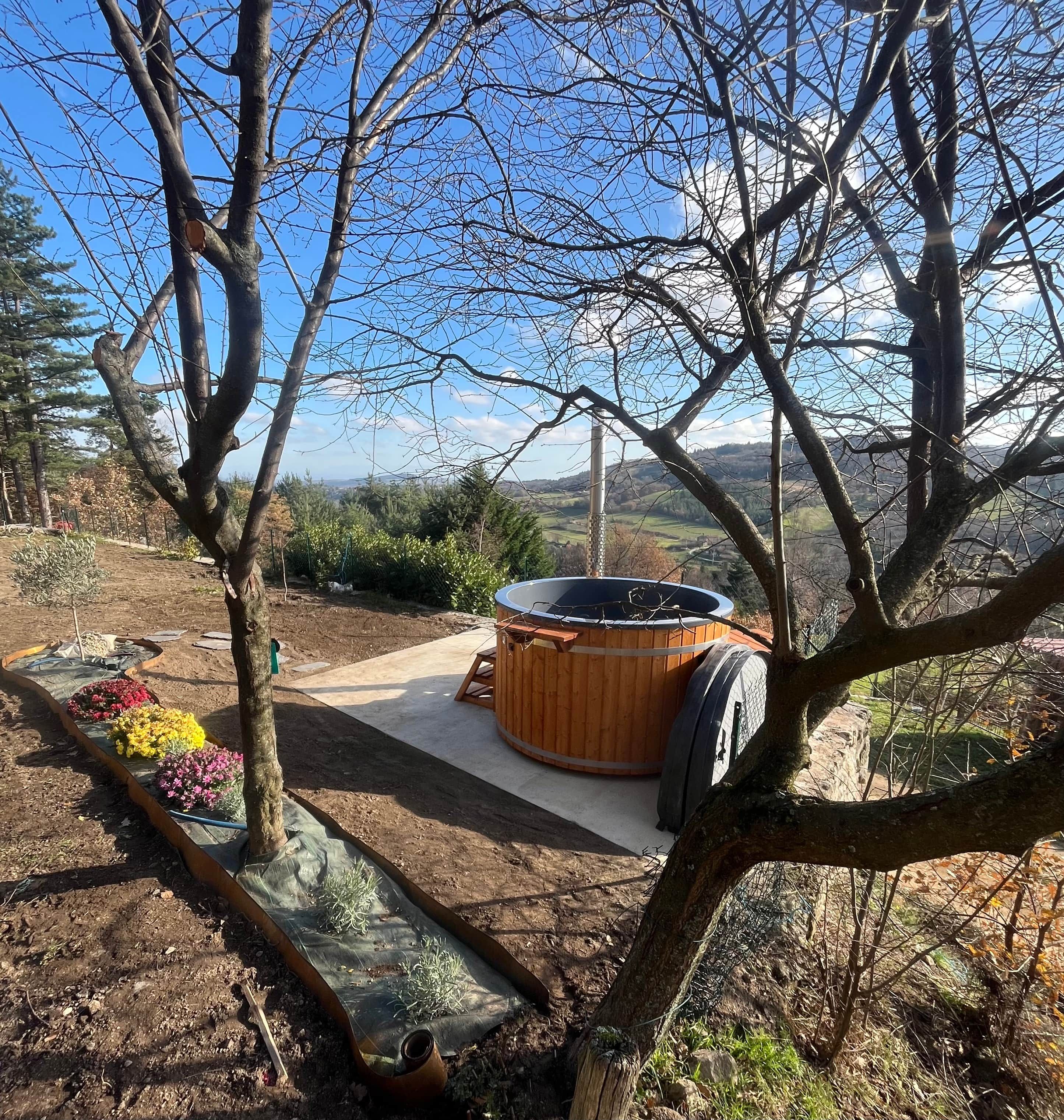 A hot tub in a garden with a view of the landscape.