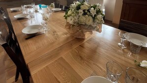 Een eetruimte met een houten tafel gedekt voor een maaltijd, een koelkast en een raam met uitzicht.