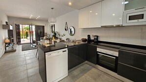 A modern kitchen with a dishwasher, oven, and microwave. There is a dining area with a table and chairs. - Casa Soleada - Three Bedroom Apartment, Sleeps 6 (Pulpí)