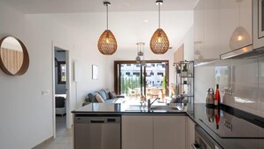 Une cuisine moderne dotée d’un îlot central, de luminaires suspendus et donnant sur un espace repas.