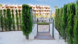 Une entrée sécurisée donnant accès à un immeuble moderne à la façade blanche et doté de balcons.