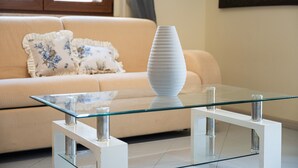 A modern living room with a glass coffee table, a beige sofa with decorative pillows, and a wall-mounted painting. - Holiday Home 'P012' with Balcony, Wi-Fi and Air Conditioning (Cagliari)