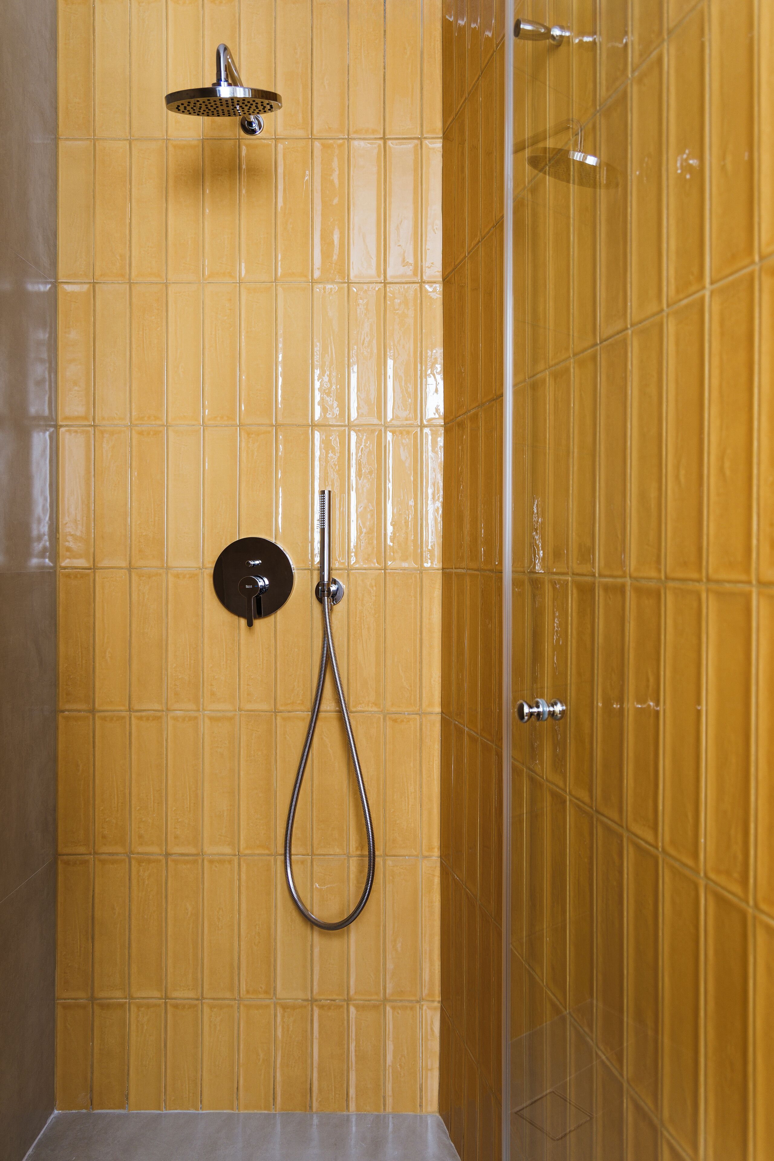 Une douche équipée d’un pommeau de douche à main et de commandes murales.