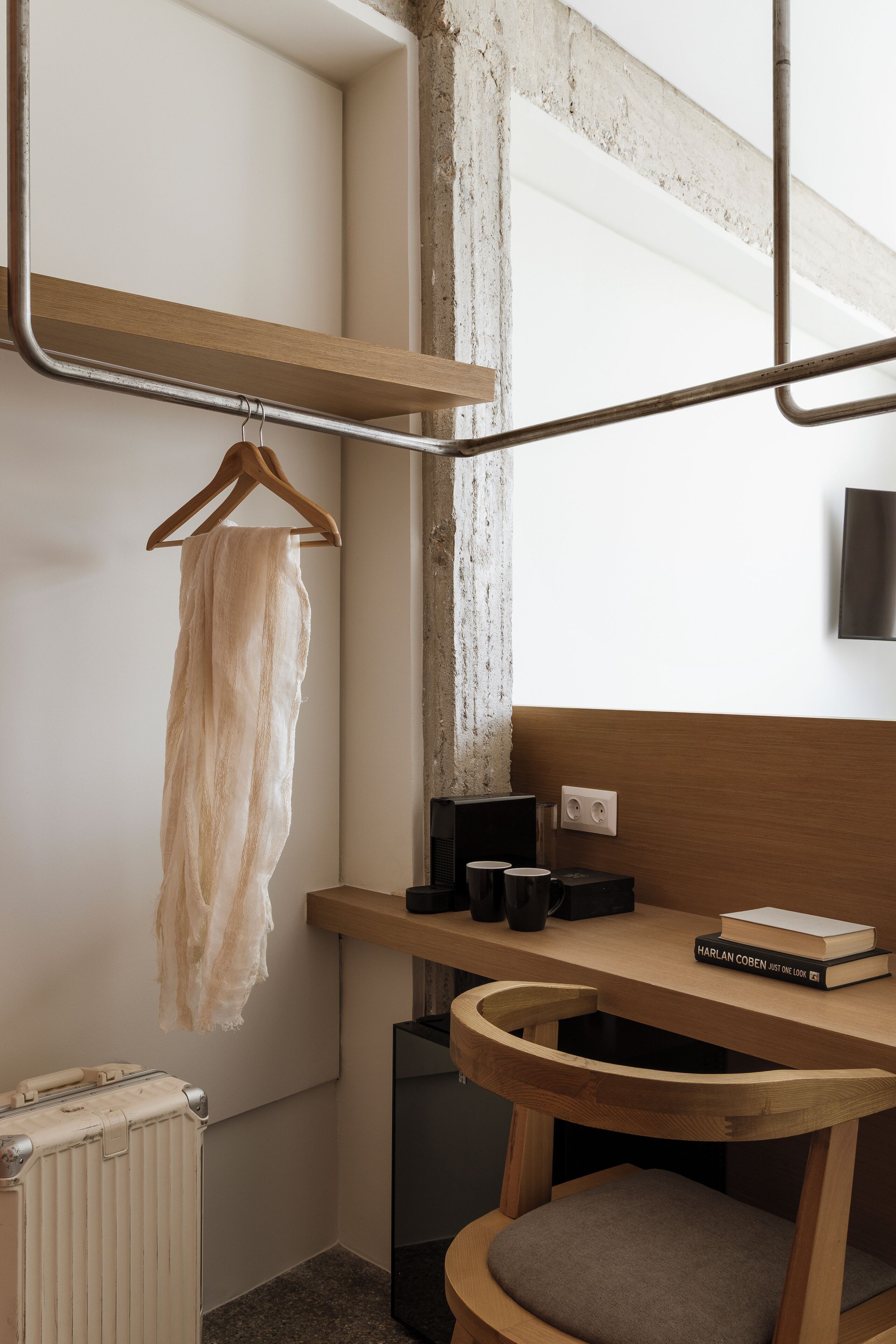 A compact room with a wooden bench, a hanging towel, a radiator, and a wall-mounted power outlet.