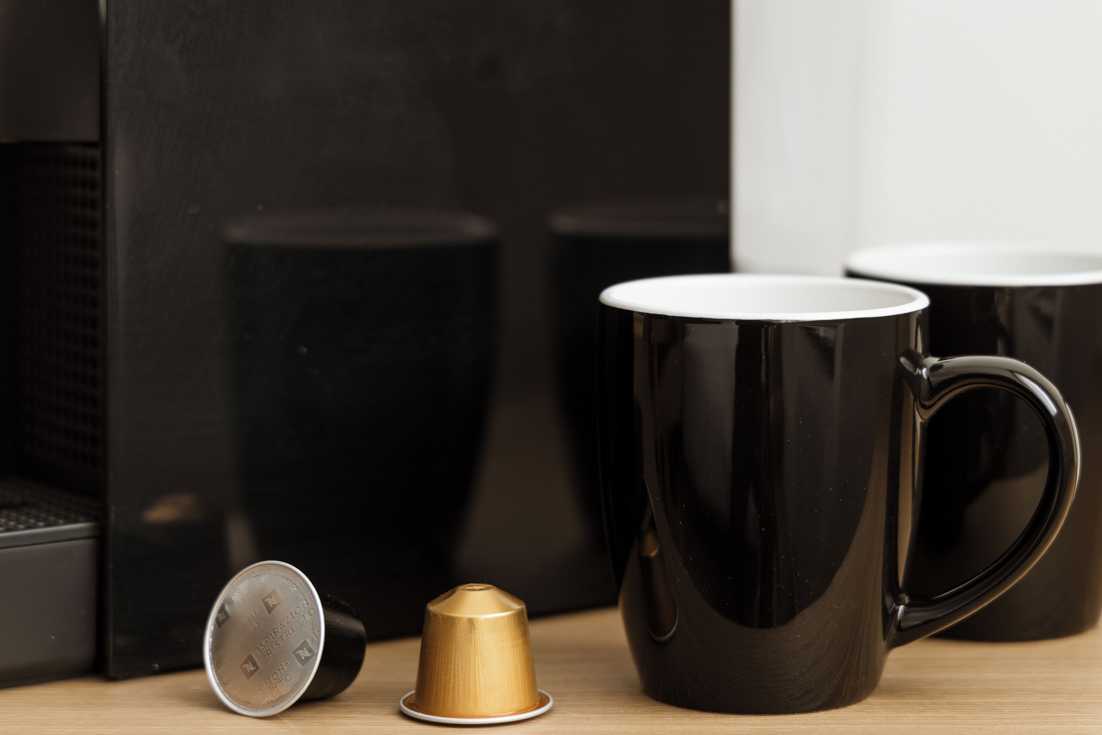 A coffee maker, a coffee cup, and a cup of coffee on a table.