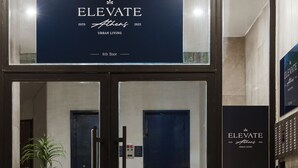 Ein Hotel Eingang mit einem Schild, auf dem steht: ELEVATE Athens 2025 URBAN LIVING 6. Etage.