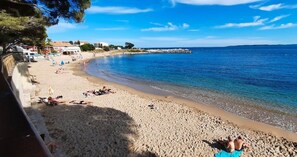 A beach with people sunbathing and swimming, a clear sky, and a calm sea.