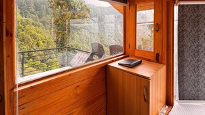 A cabin with wooden walls and a large window offering a view of a forested area. - The Grand Resort (Dhanaulti)