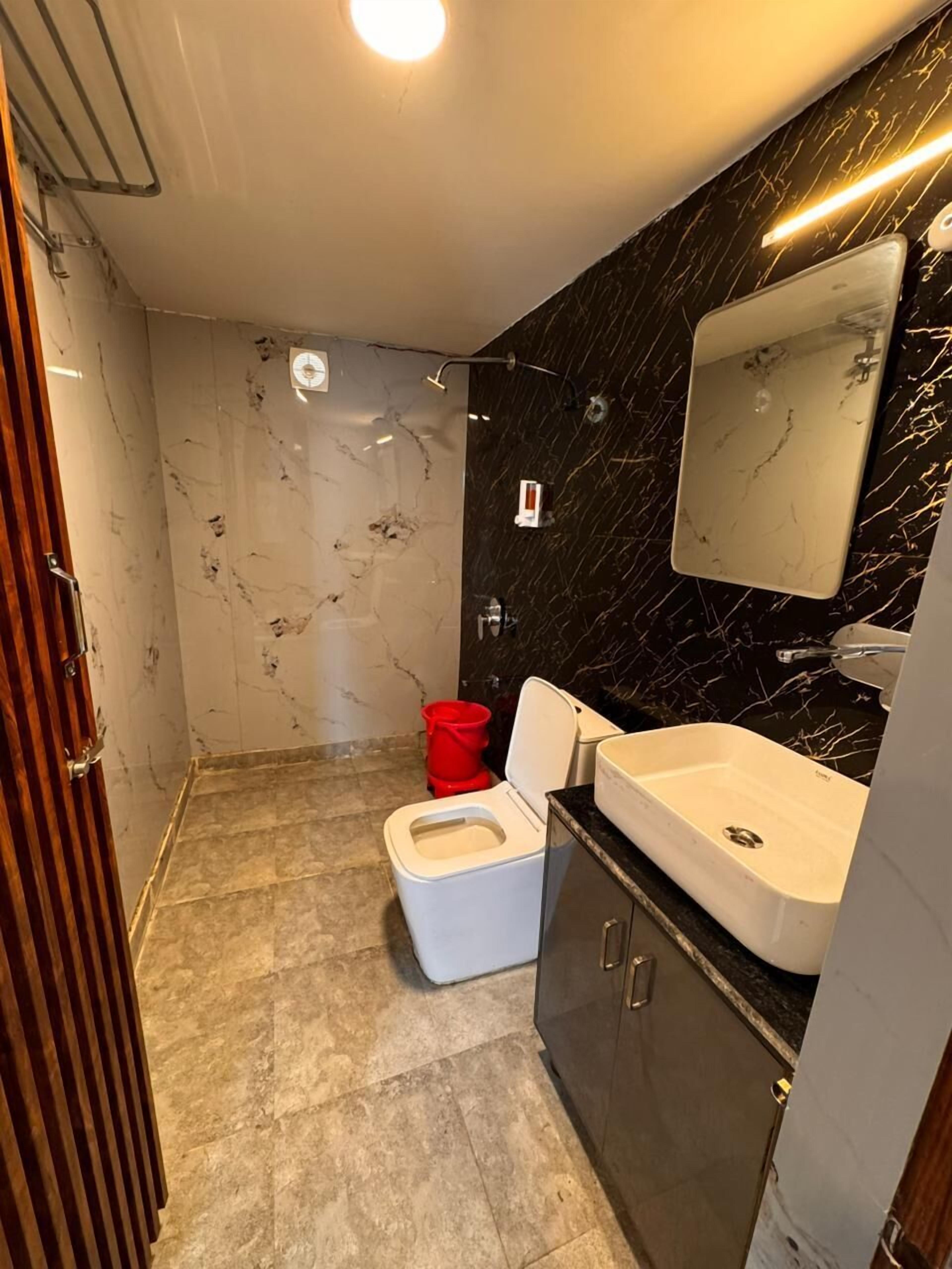 Egy modern fürőszoba, amelyben WC, mosdókagyló és tükör található.