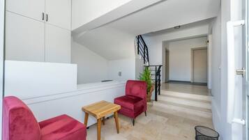 Un salon moderne avec un fauteuil en velours rouge, une table en bois et un meuble blanc.