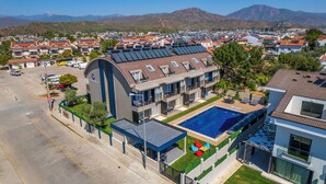A modern hotel with a rooftop pool, solar panels, and a view of the surrounding town and mountains. - Dede Suites Fethiye (Fethiye)