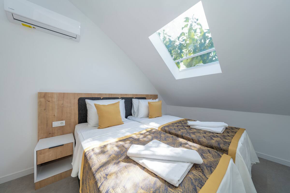 A bedroom with two beds, a skylight, and a built-in shelf.