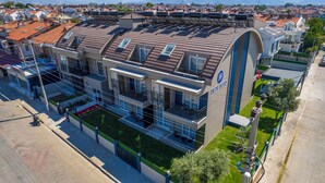 A modern building with multiple balconies, solar panels, and a sign reading "DEDE SUIIS". - Dede Suites Fethiye (Fethiye)