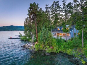 A lakeside cabin with a dock, surrounded by dense forest and hills in the background. - Caroline Point Retreat (Lakeside)