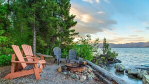 Een zitgedeelte aan het meer, met Adirondack-stoelen en een vuurkuil.