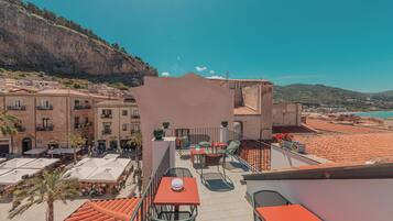 Una terraza en la azotea con mobiliario exterior, vistas del pueblo y un acantilado al fondo.