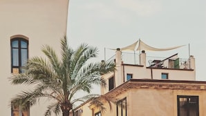 A building with a balcony and a palm tree in front. - Palazzo Villelmi (Cefalù)