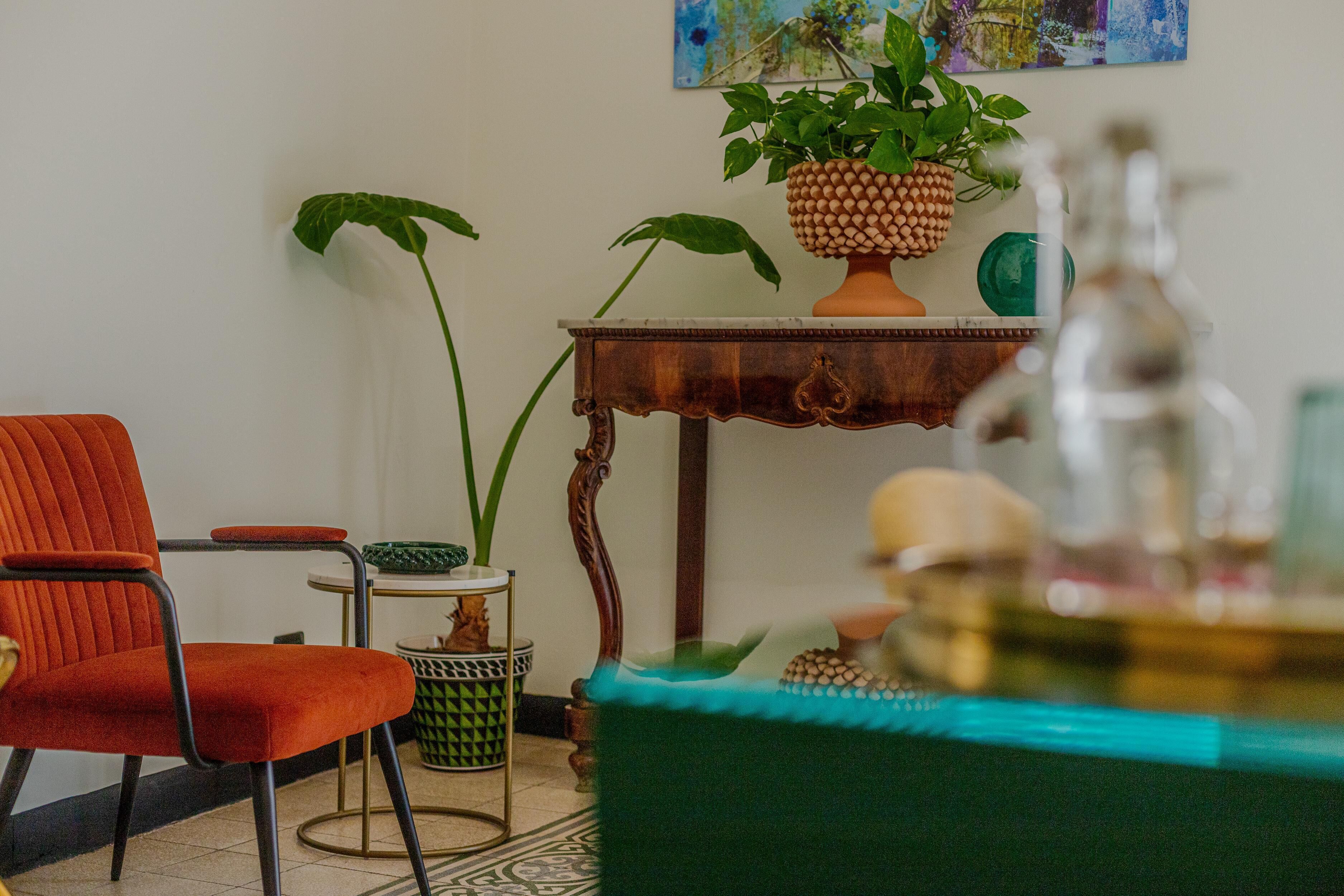 A room with a red chair, a wooden table with a potted plant, and a green sofa.