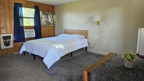 Een slaapkamer met een bed, een wandlamp, een tafeltje en een radiator.