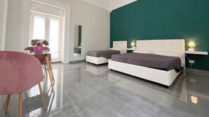 A modern hotel room with a large bed, two bedside tables, a desk with a chair, and a mirror. - DC House (Procida)
