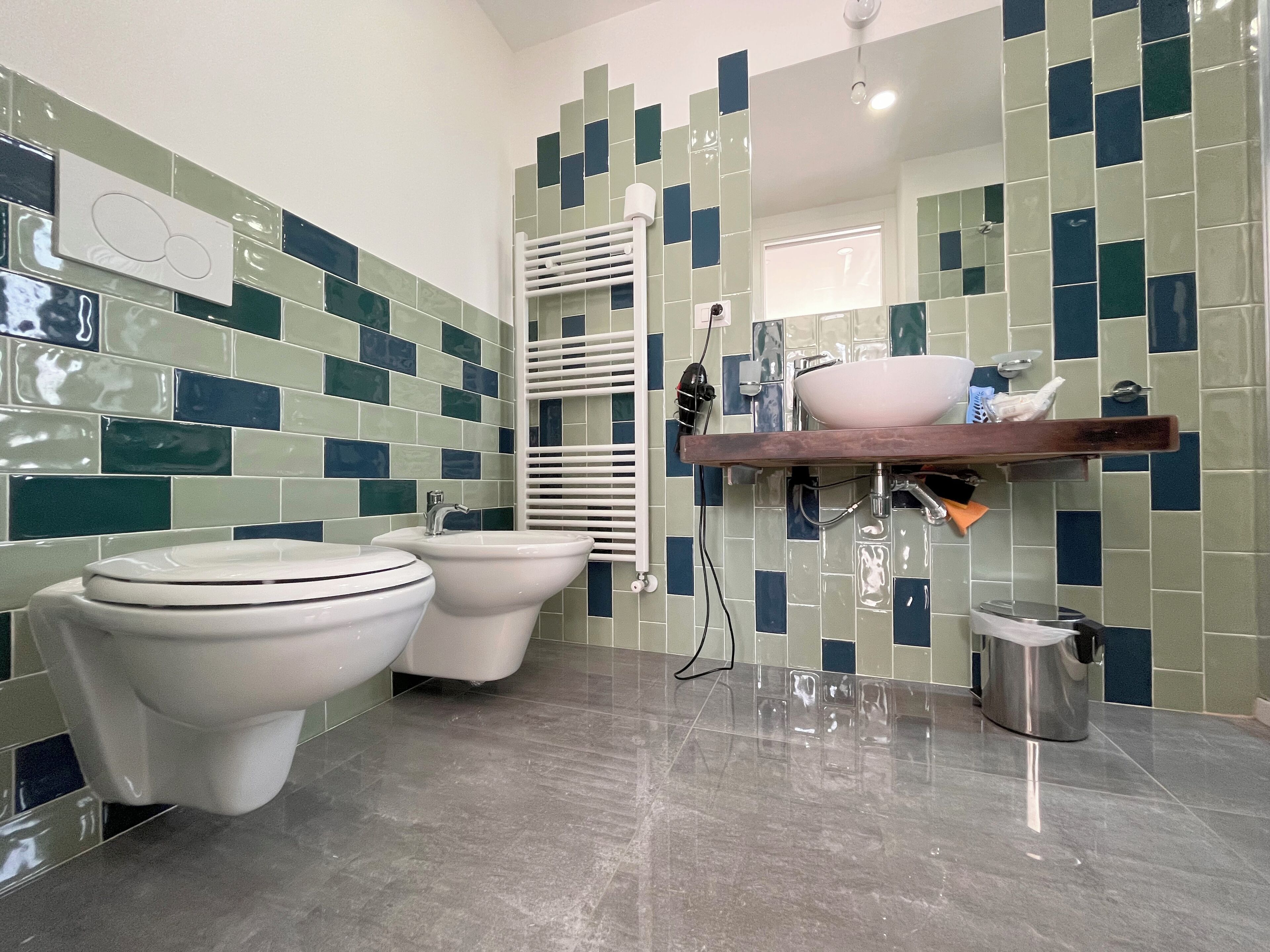 Een badkamer met twee toiletten, een wastafel, een spiegel en een douchehoek.