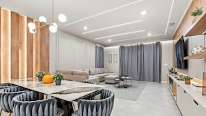 A modern living room with a dining area, a sofa set, and a TV mounted on the wall. - 7BR house sleeps 24 with game room (Clermont)