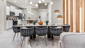 A modern kitchen with white cabinets, a central island with bar stools, and a wooden accent wall. - 7BR house sleeps 24 with game room (Clermont)
