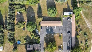 An aerial view of a property with a parking lot, a building with a flat roof, and surrounding greenery. - Basic Room, 1 Double Bed #8 (Hart)