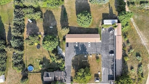 Vue aérienne d’une propriété comprenant un parking, un bâtiment doté d’un toit plat et des espaces verts environnants.