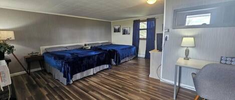 A room with two beds, a desk, and a chair.