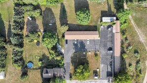 Luchtbeeld van een pand met een groot gebouw, een parkeerplaats en omliggend groen.