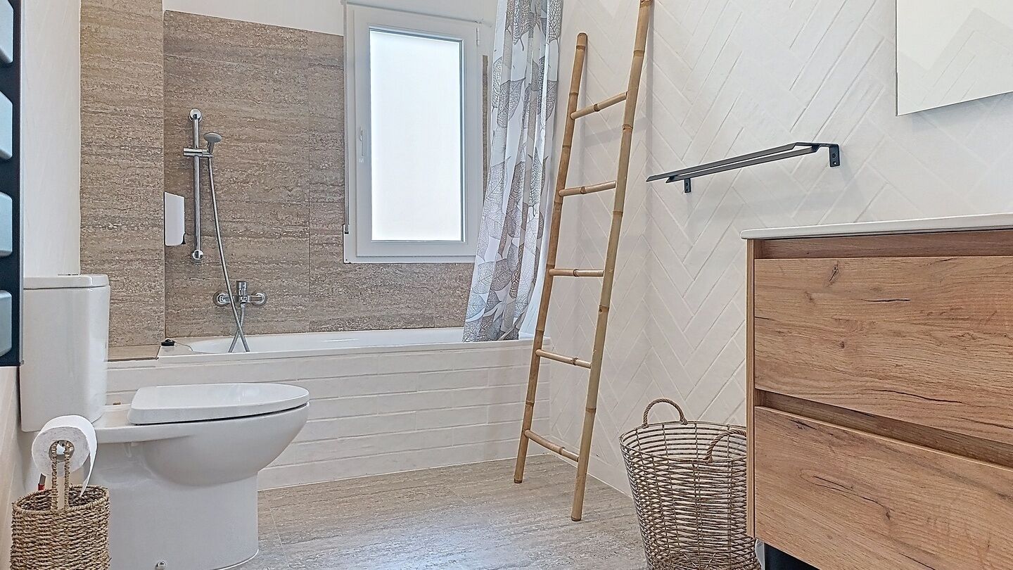 Un baño con bañera, inodoro y ventana.