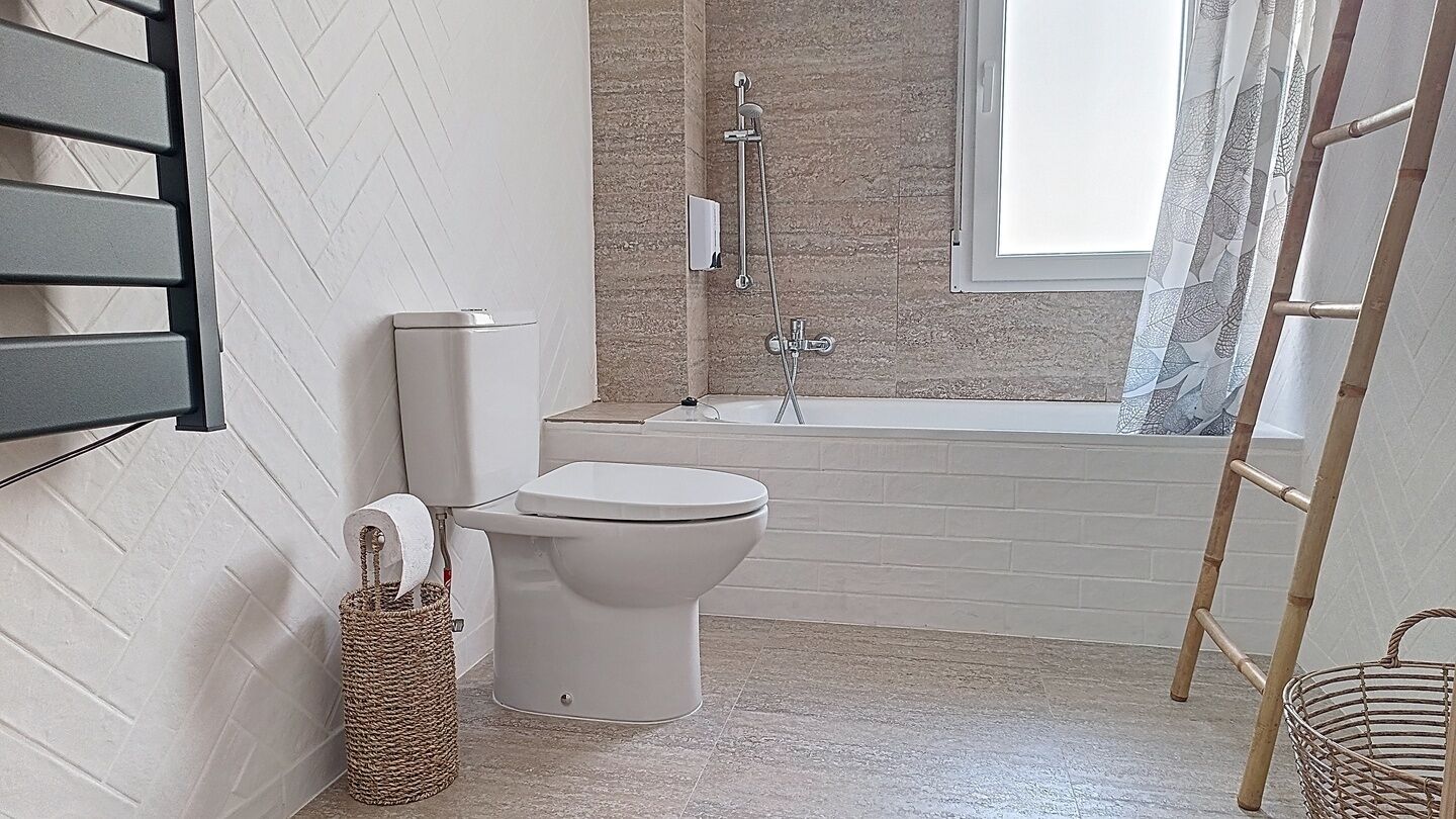 Un baño con inodoro, bañera, ducha y ventana.
