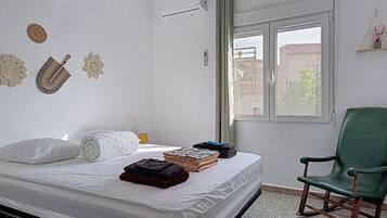 A bedroom with a bed, a chair, and decorative wall art.