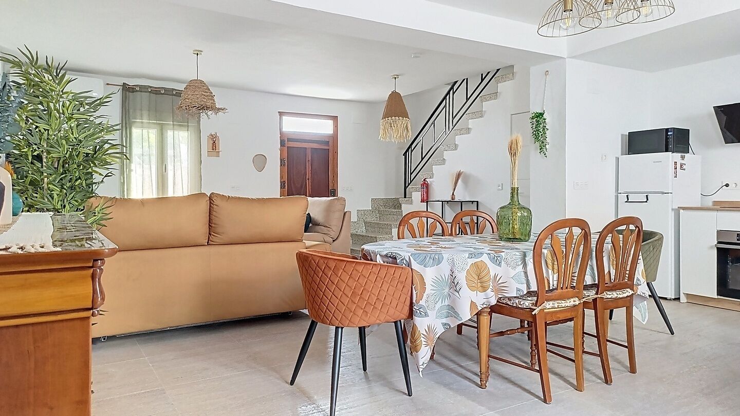 Una sala de estar con sofá, mesa de comedor, sillas y una zona de cocina.