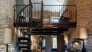 A multi-level stone interior with a spiral staircase, multiple lamps, and a chandelier. - Luxury Mas in Gordes with pool & view Charming comfort and privacy (Gordes)