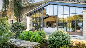 A modern house with a stone facade, large glass windows, and a well-maintained garden. - Luxury Mas in Gordes with pool & view Charming comfort and privacy (Gordes)