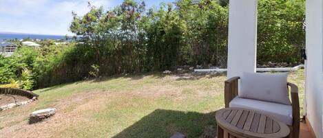 A covered outdoor seating area with a view of a grassy yard and trees.