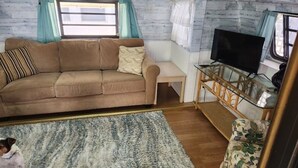 Een gezellige woonkamer met een bank, een televisie en een kleine tafel.