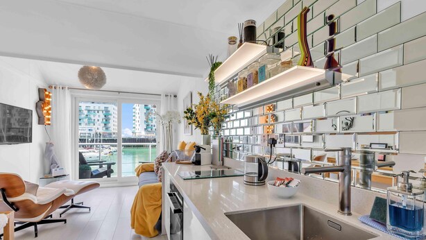 A modern kitchen with a large island, stainless steel appliances, and a view of the city through large windows. - On the Water 7| Free Parking | By My Getaways (Brighton)