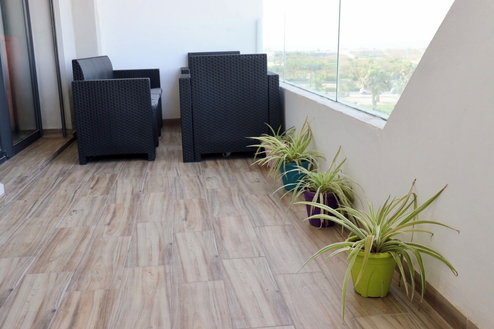 Een balkon met rieten meubilair en plantenpotten.