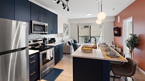 Una cocina moderna con electrodomésticos de acero inoxidable, una isla central y un comedor con una mesa larga.