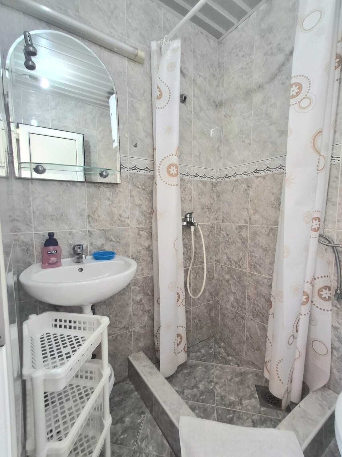 Un baño con ducha, lavamanos y espejo.