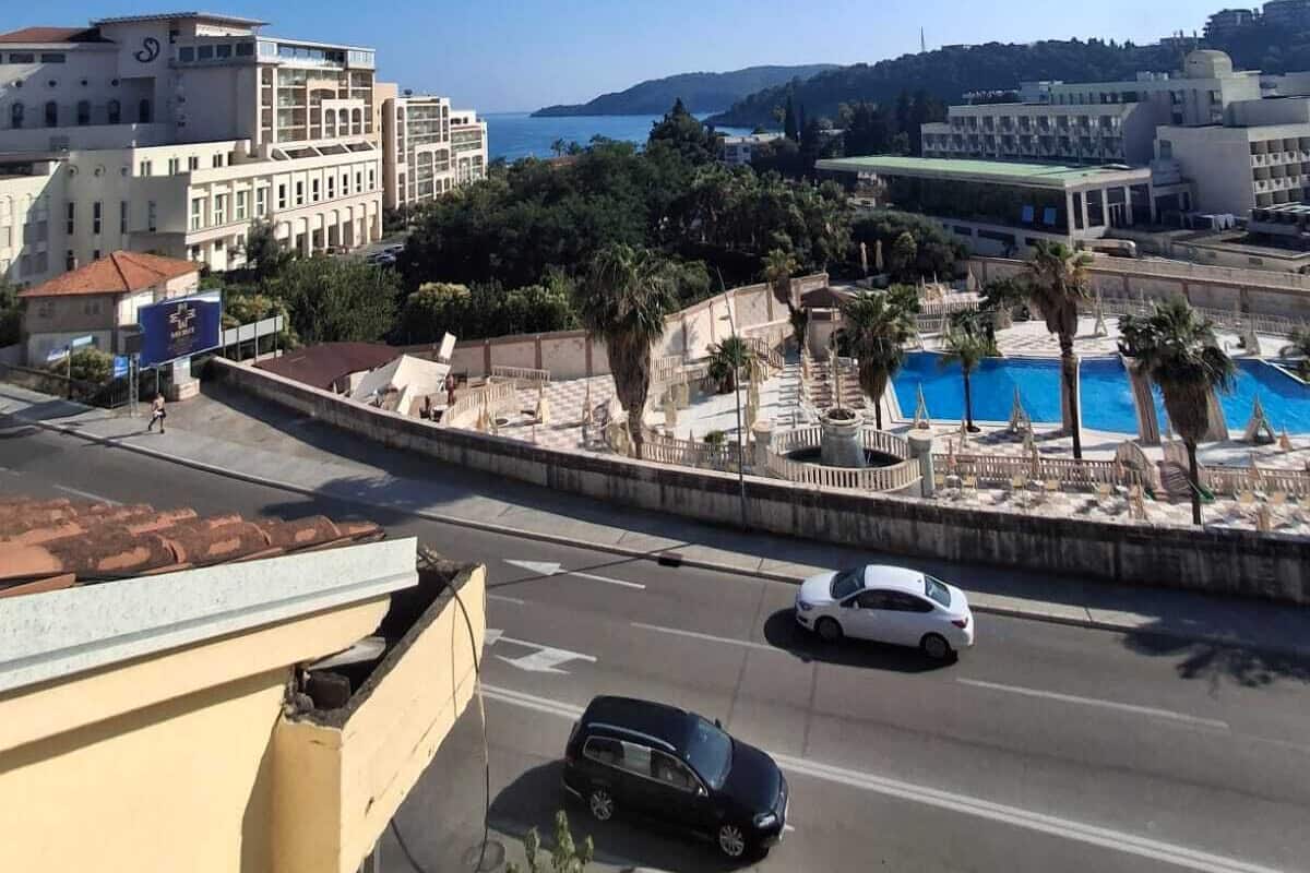 Ein Hotel mit Pool, eine Straße mit Autos und Gebäude im Hintergrund.