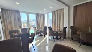 Une chambre d’hôtel moderne dotée d’un coin repas, de grandes fenêtres et d’une vue sur la ville.