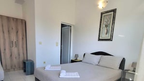 Une chambre à coucher moderne avec un grand lit, une armoire, une table de chevet et un tableau encadré au mur.