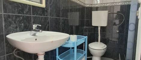 Un baño con lavamanos blanco, inodoro y zona de ducha.