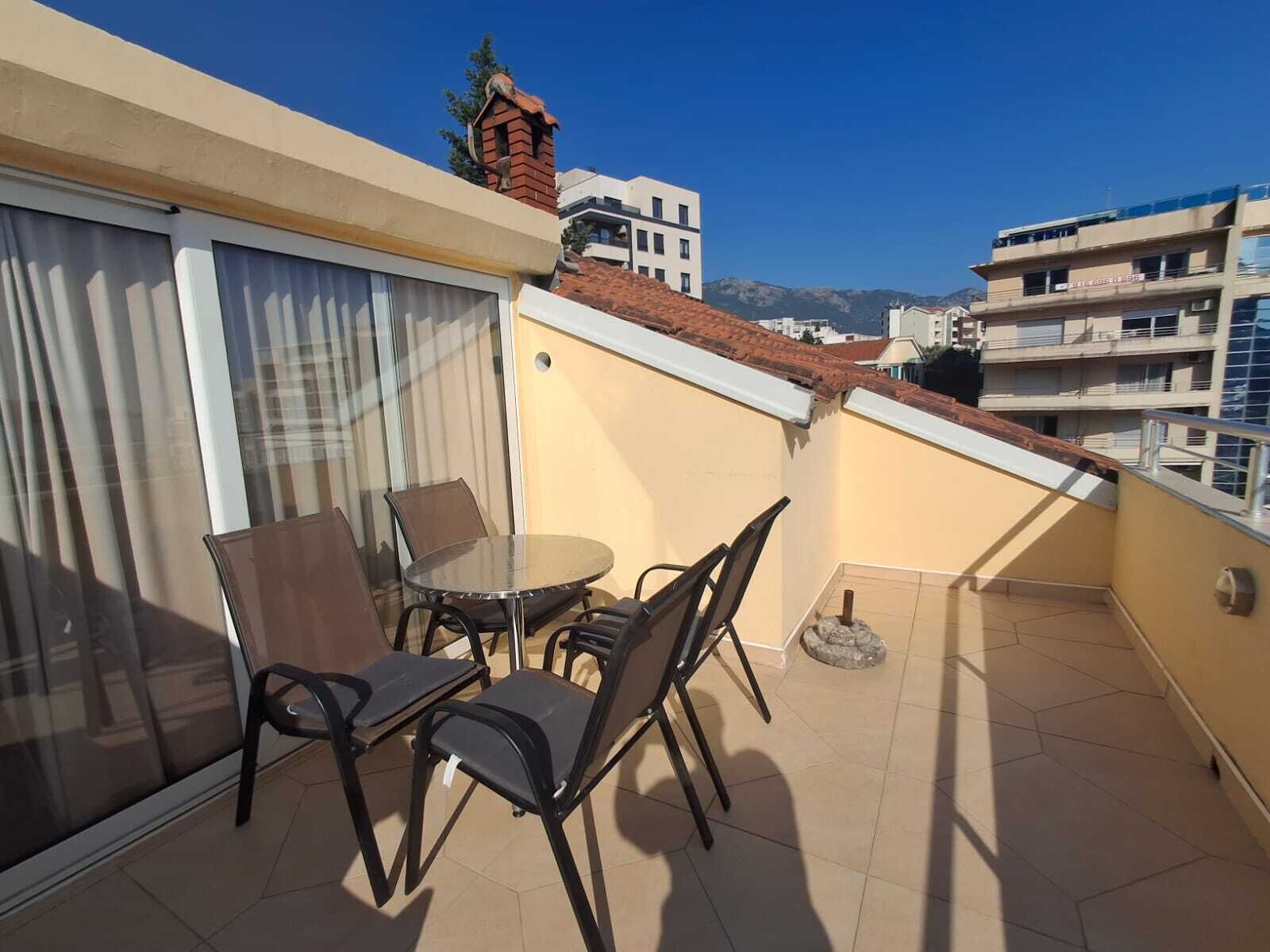 Un balcone con una porta vetrata, un tavolo rotondo e quattro sedie.
