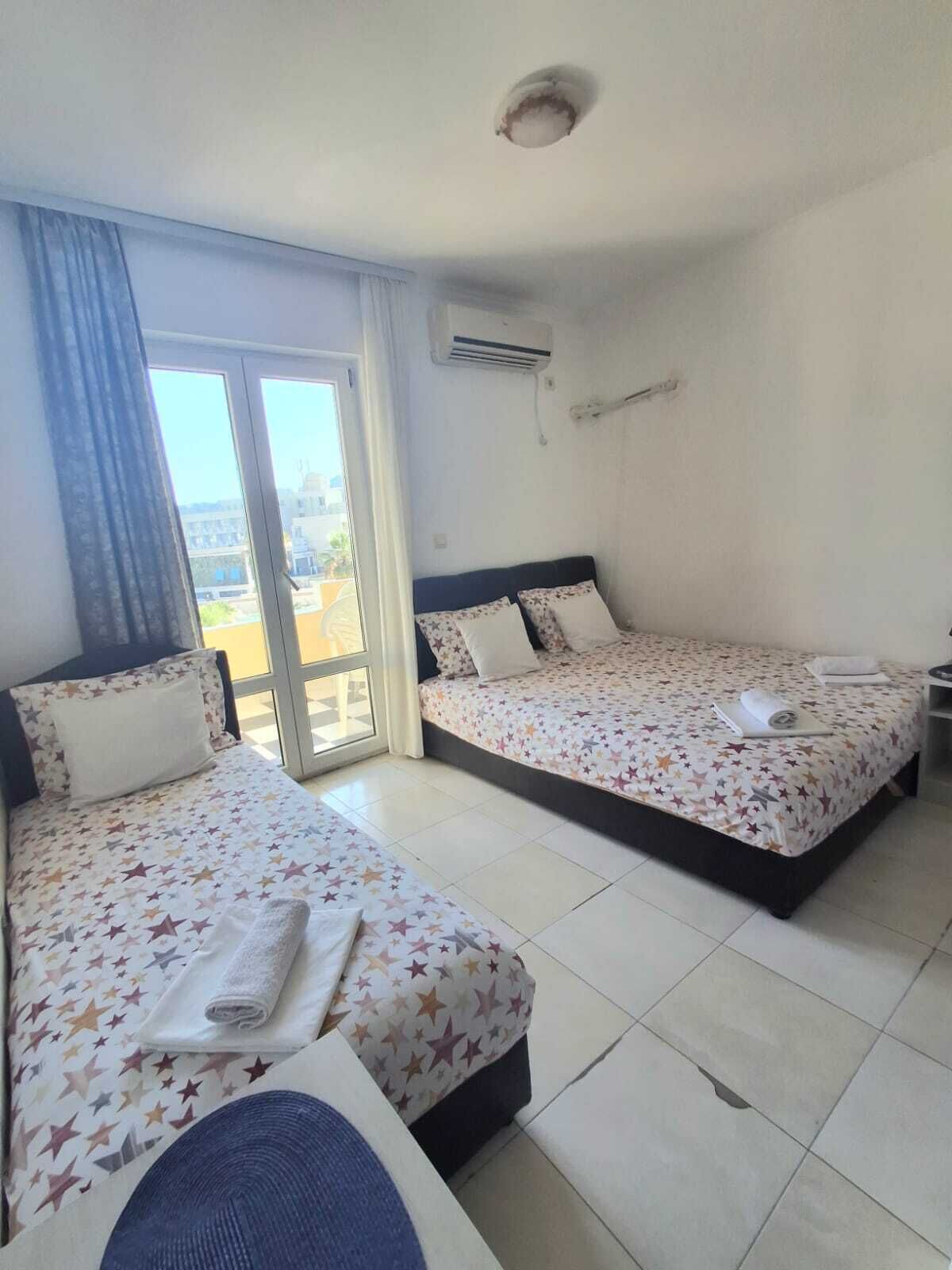 Une chambre d’hôtel avec deux lits, une grande fenêtre et un appareil de climatisation.