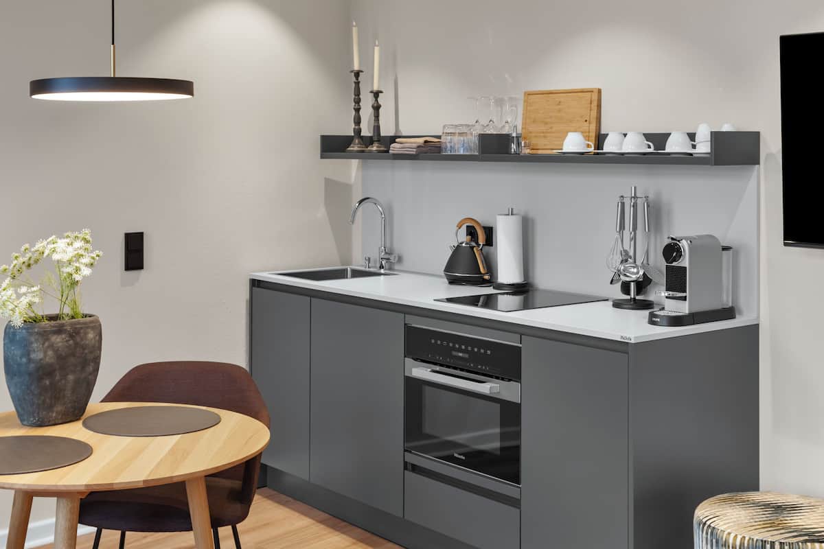 A modern kitchen with a built-in oven, a coffee machine, and a sink.